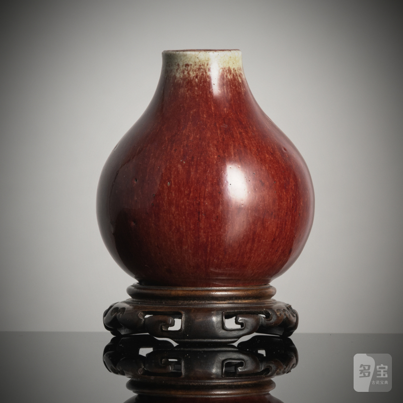 A small oxblood-glazed porcelain vase on wood stand
